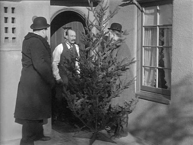 Oliver Hardy and Stan Laurel offer a Christmas tree to James Finlayson at his front door in Big Business (1929)
