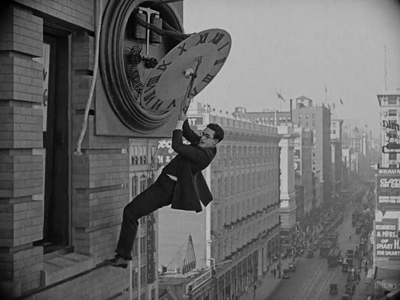 Harold Lloyd hangs from the hands of a giant clock high above a busy city street in Safety Last! (1923)