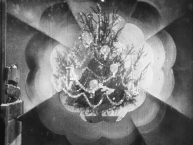A Christmas tree hung with tinsel glows inside a stylised burst of light in Jean Renoir's The Little Match Girl (1928)